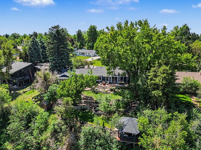 Property Photo 34 A true backyard paradise! This perspective captures the entire multi-level estate, showcasing the stunning covered gazebo, tiered stone retaining walls, expansive brick patios, and incredible privacy tree canopy.