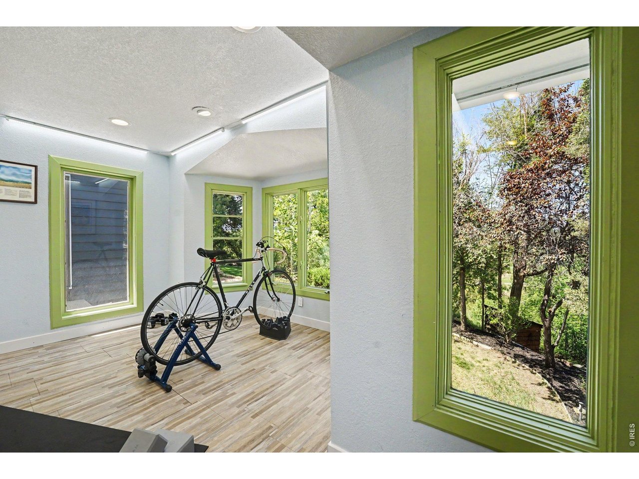 This bright and flexible studio space features wrap-around windows that frame peaceful backyard, making it an inspiring setup.