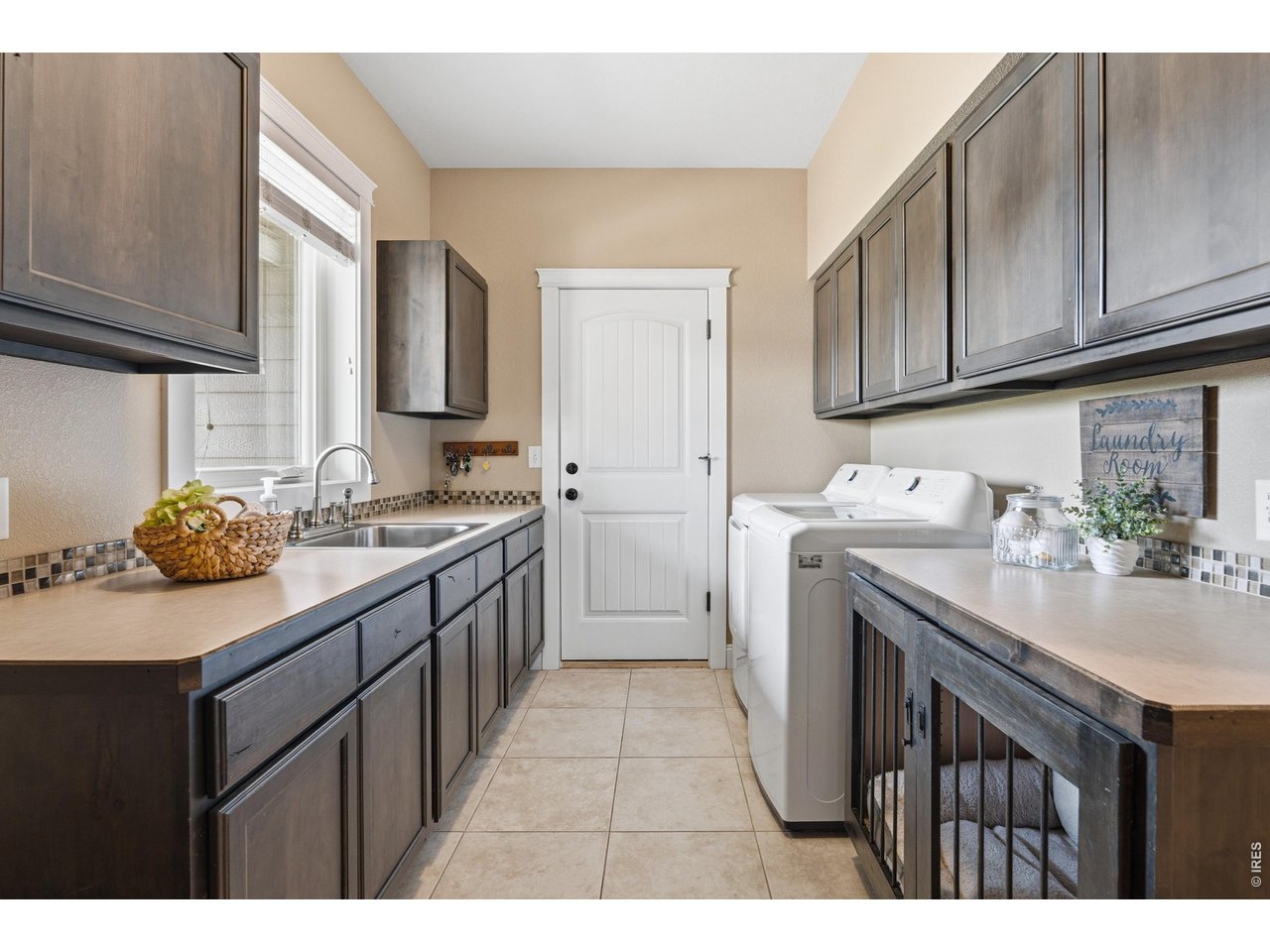 Laundry room off of garage with utility sink and cabinets