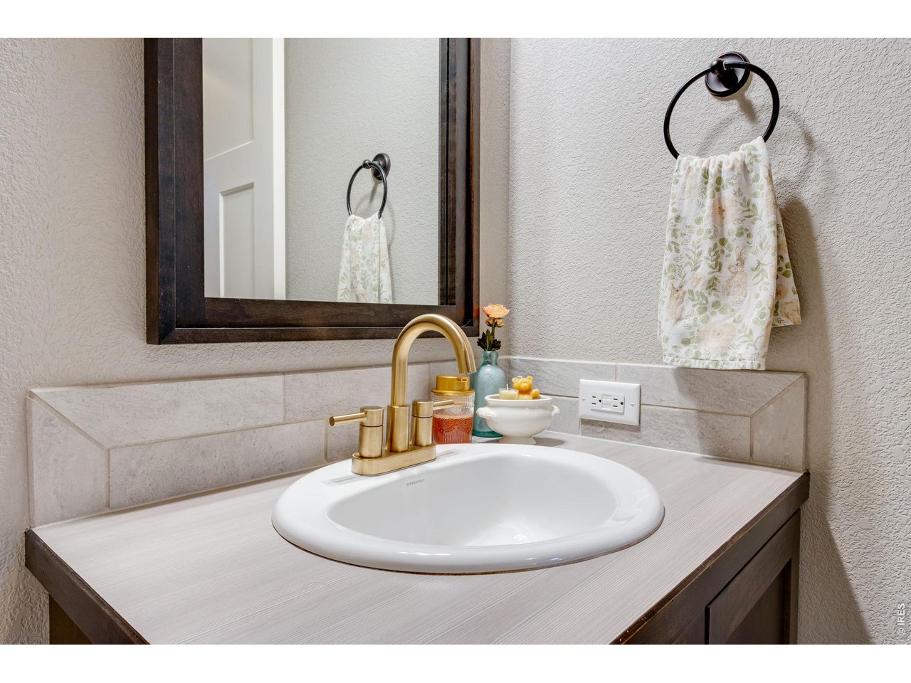Guest bath featuring a vanity with rustic brass faucet, upgraded mirror and light fixture 