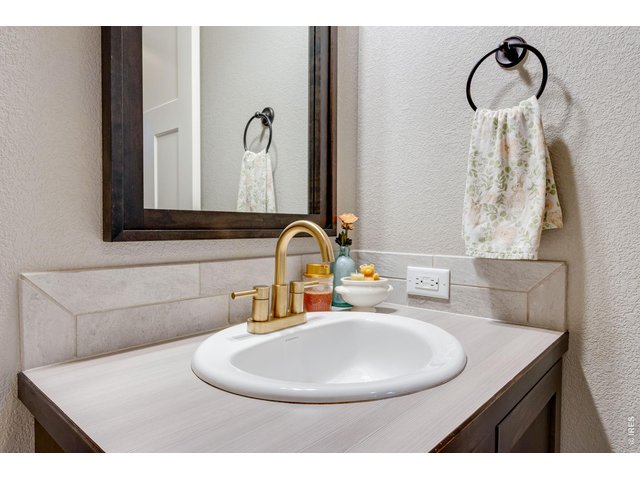 Property Photo 21 Guest bath featuring a vanity with rustic brass faucet, upgraded mirror and light fixture 