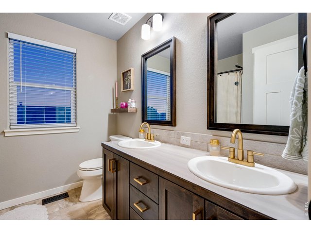 Property Photo 32 Full bath featuring 2 vanities with modern rustic brass faucets, toiler with soft-close lid, upgraded mirrors and light fixtures plus a deep linen closet located behind door