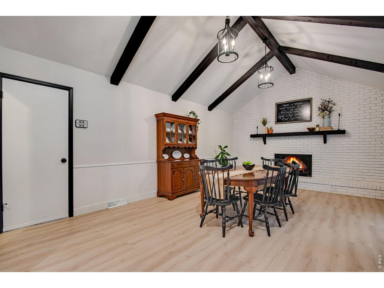 Family room features 2 light fixtures, exposed trusses, a wood burning fireplace with brick backsplash and a double wide mantel