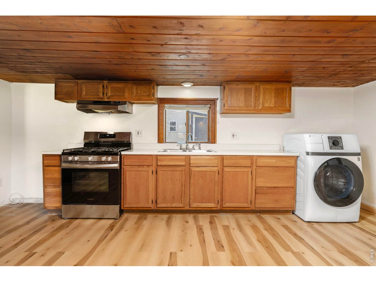 Kitchen area with one year old gas stove and unused oven. Along with a clothes washer/dryer combo, also one year old.