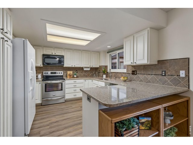Property Photo 18 A spacious kitchen featuring quartz countertops, tile backsplash, painted cabinetry, and generous prep space for both daily living and entertaining