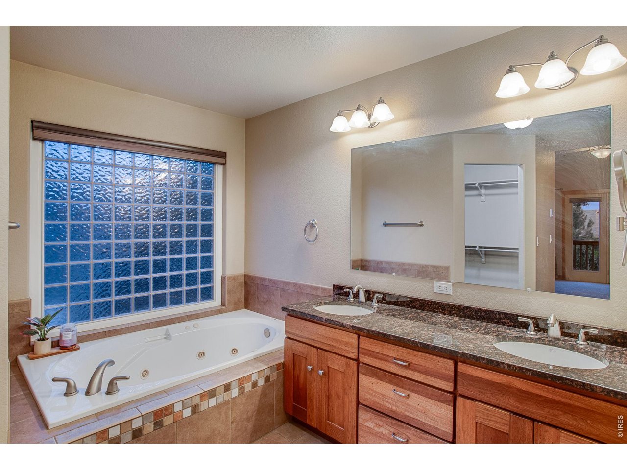 Property Photo 23 5-piece luxury bath featuring a linen closet, walk-in closet with attic access, tile flooring, shower with full tile backsplash, two raised vanities, granite slab countertops, soaking tub, and a private water closet