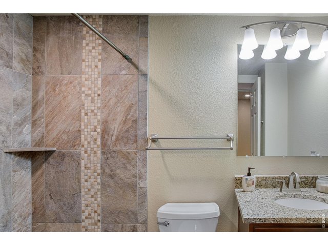 Property Photo 37 bath featuring a vanity with granite slab countertop and shower with full tile backsplash
