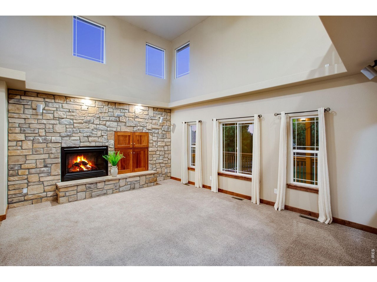Property Photo 9 Large living room features a gas fireplace with blower and full stone backsplash, vaulted ceilings, fan, and surround sound