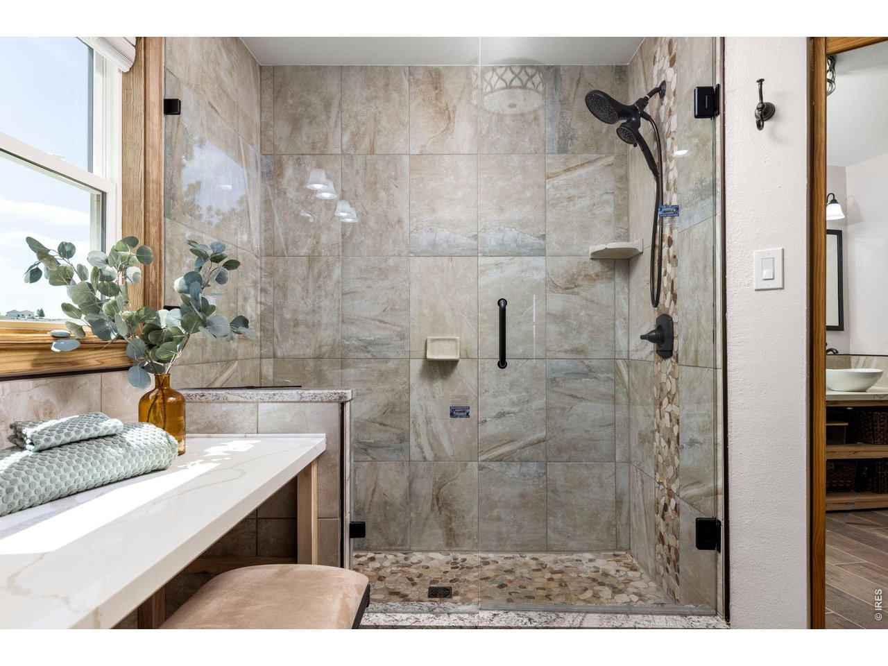 Property Photo 19 Custom tile finishes and a glass-enclosed shower complement the primary bathroom.
