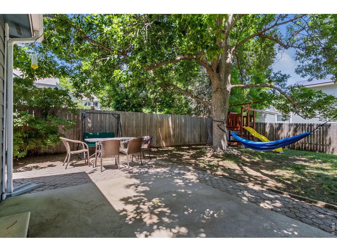 Property Photo 22 The backyard patio is ready for summer barbecues, outdoor dining, and relaxing evenings under the shade trees.