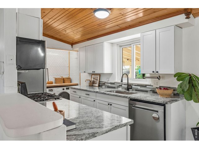 Property Photo 9 Updated kitchen features white shaker cabinets, granite counters, gas range, and stainless appliances.