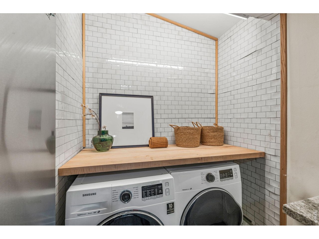 Tucked-away laundry nook with subway tile and butcher block counter, full size washer and dryer included.