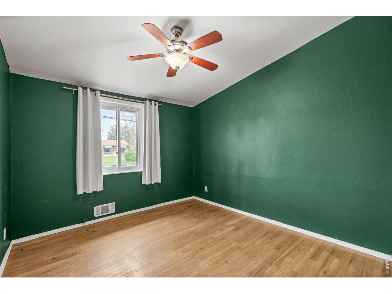 bedroom with deep emerald green accent walls, original hardwood floors, and great closet space.