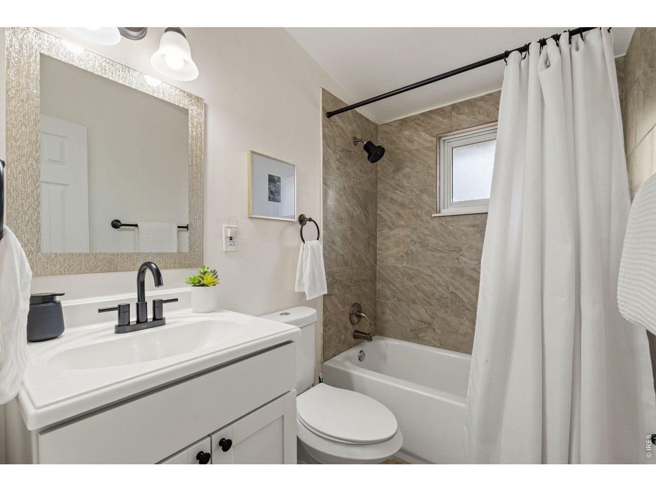 Updated full bathroom with new tile surround, modern vanity, and matte black fixtures.