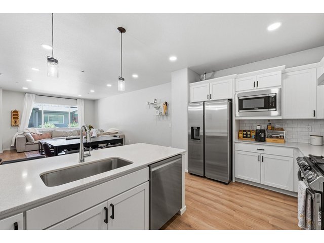Property Photo 17 Stylish kitchen with stainless steel appliances, a dual-fuel gas range with vent hood, white maple cabinetry, subway tile backsplash, quartz countertops, pantry, and large breakfast bar