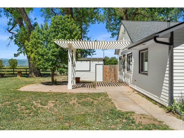 Property Photo 39 The shed behind the pergola features a TV behind the dropdown window for outdoor entertainment