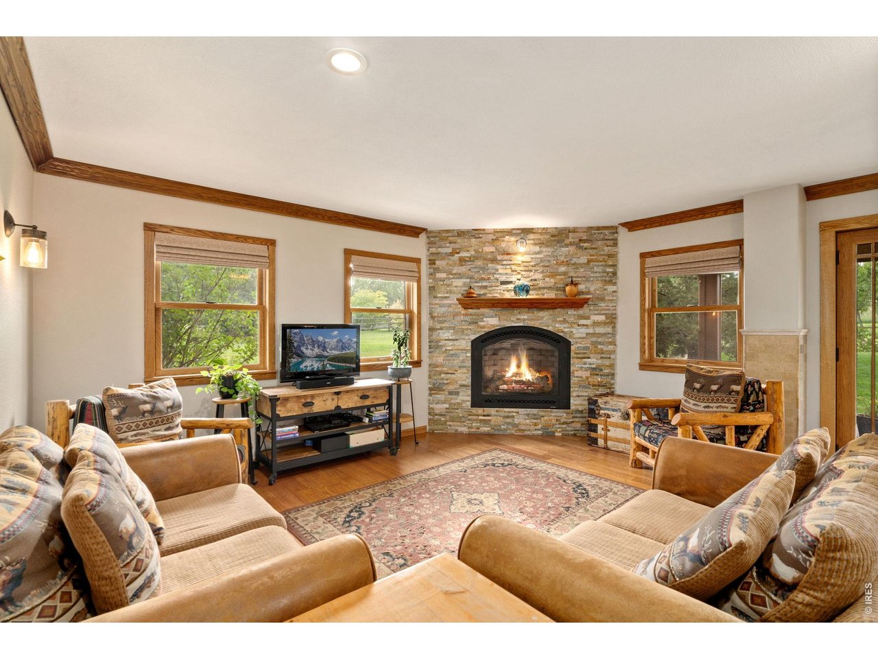 This family room is the perfect place to relax, featuring a second fireplace, lounging areas, engineered wood floors and doors to backyard