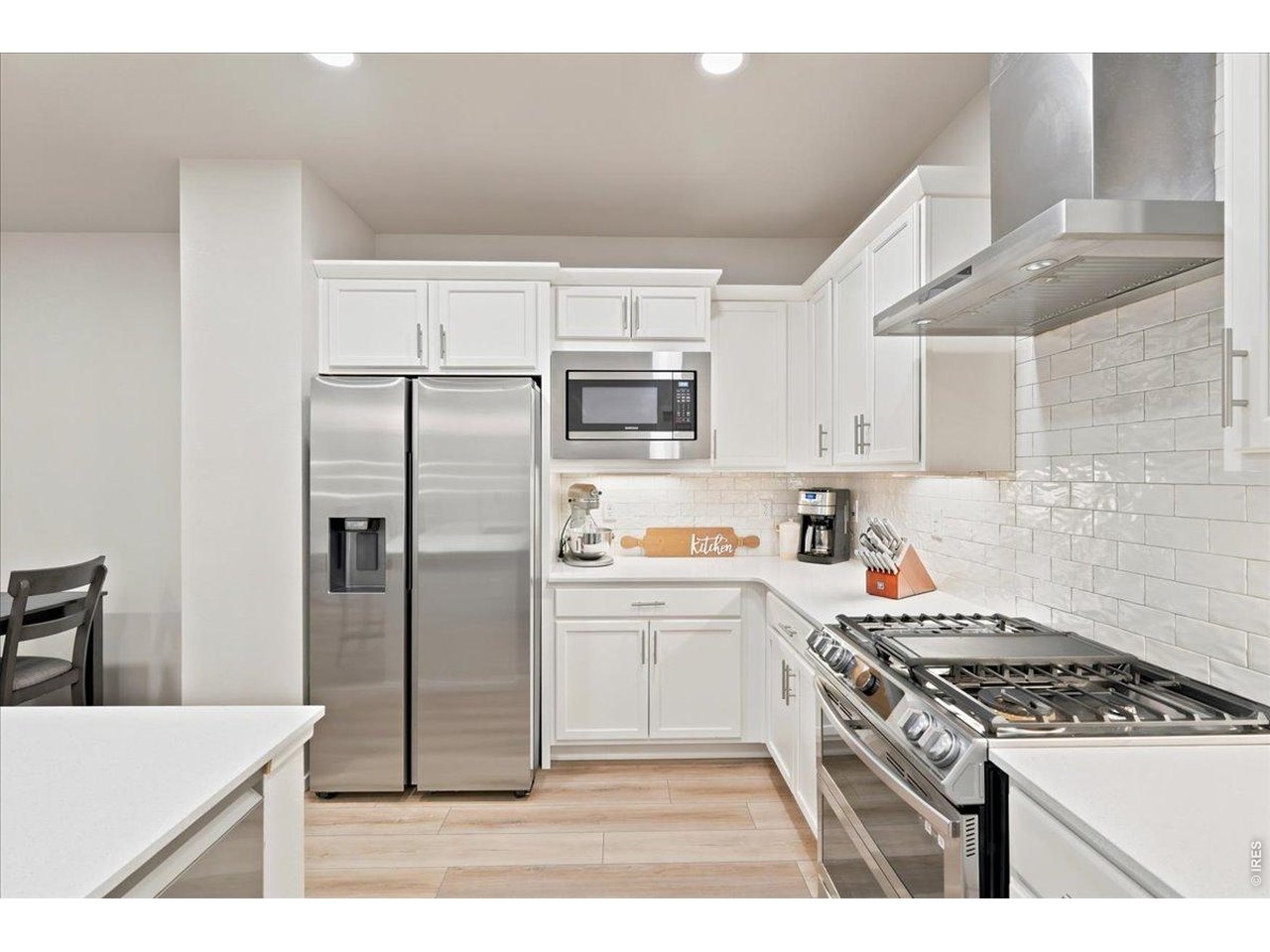 Property Photo 3 Stainless appliances, subtle subtle tile backsplash, and a sleek vent hood.