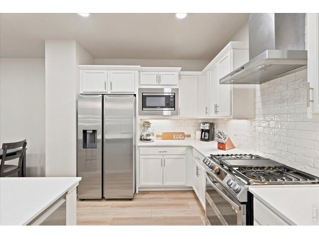 Property Photo 3 Stainless appliances, subtle subtle tile backsplash, and a sleek vent hood.