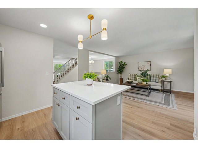 Property Photo 12 Kitchen island with its light stone countertop and updated cabinetry looking out into the open family room.