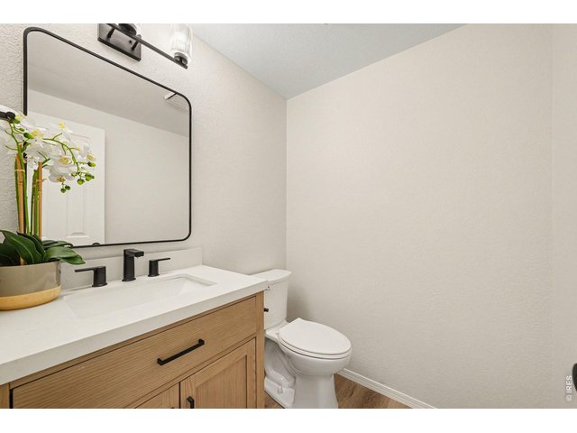 Property Photo 25 Updated 1/2 bathroom featuring a light stone countertop over wood cabinetry, modern black fixtures, and a stylish framed mirror.