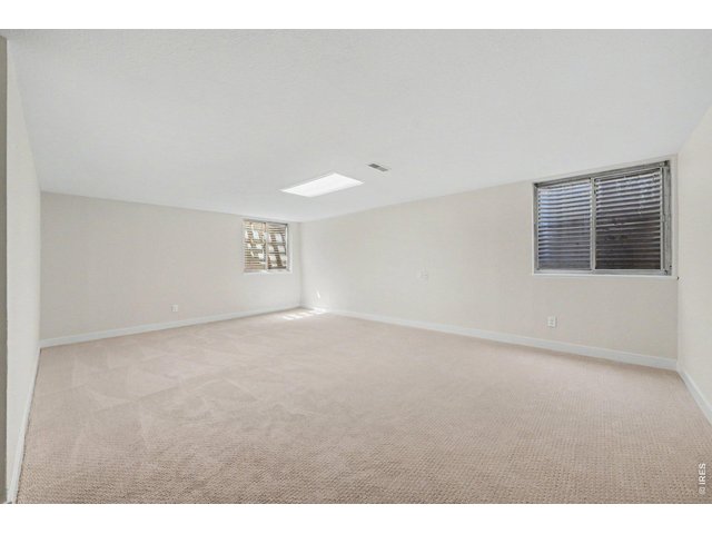 Property Photo 26 Expansive, freshly carpeted basement rec room or additional living space, offering excellent layout flexibility and natural lighting via window wells.