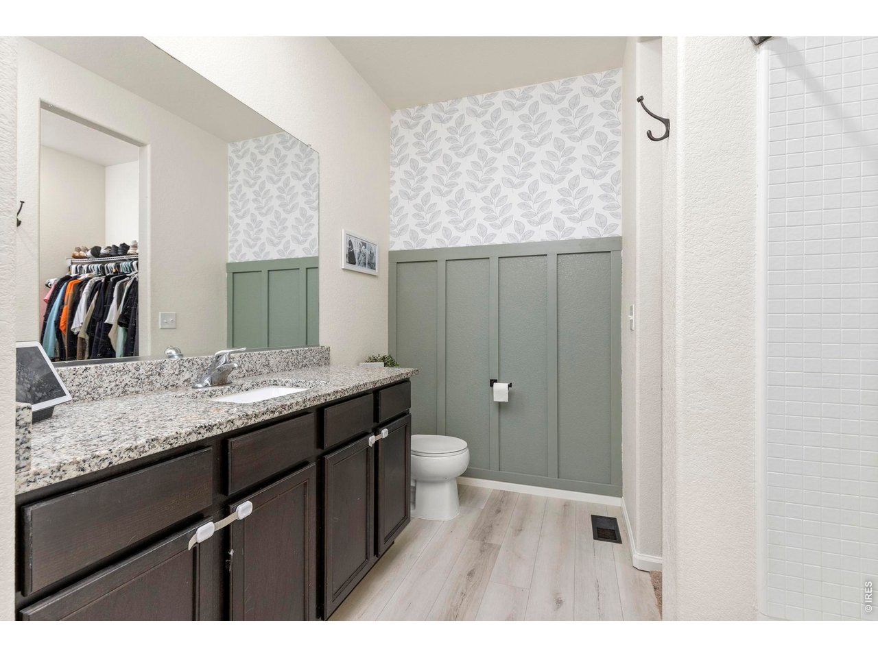 Property Photo 14 The primary suite includes a full en-suite bathroom with granite countertops, a board and batten accent wall, and a large walk-in closet.
