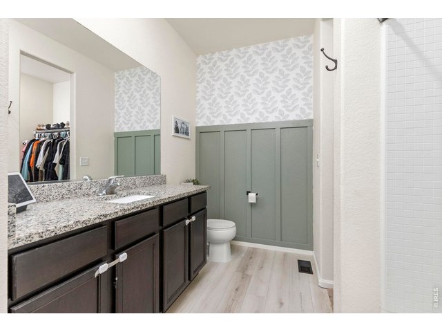 Property Photo 14 The primary suite includes a full en-suite bathroom with granite countertops, a board and batten accent wall, and a large walk-in closet.
