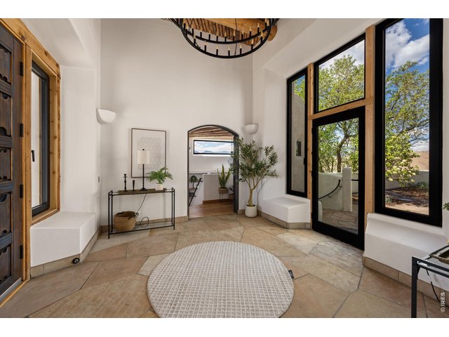 Property Photo 5 A light-filled foyer with soaring ceilings and handcrafted details opens seamlessly to a private courtyard, creating an inviting indoor-outdoor entry experience.