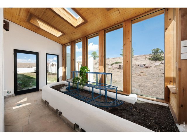 Property Photo 23 An attached solarium filled with natural light from skylights, featuring outdoor access, built-in drainage, and a hose bib for effortless plant care and year-round enjoyment.