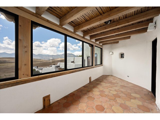 Property Photo 22 A three-season attached porch with a kiva fireplace offers a cozy extension of the home, perfectly positioned off the living room and kitchen to take in sweeping west-facing mountain views. 25 x 10
