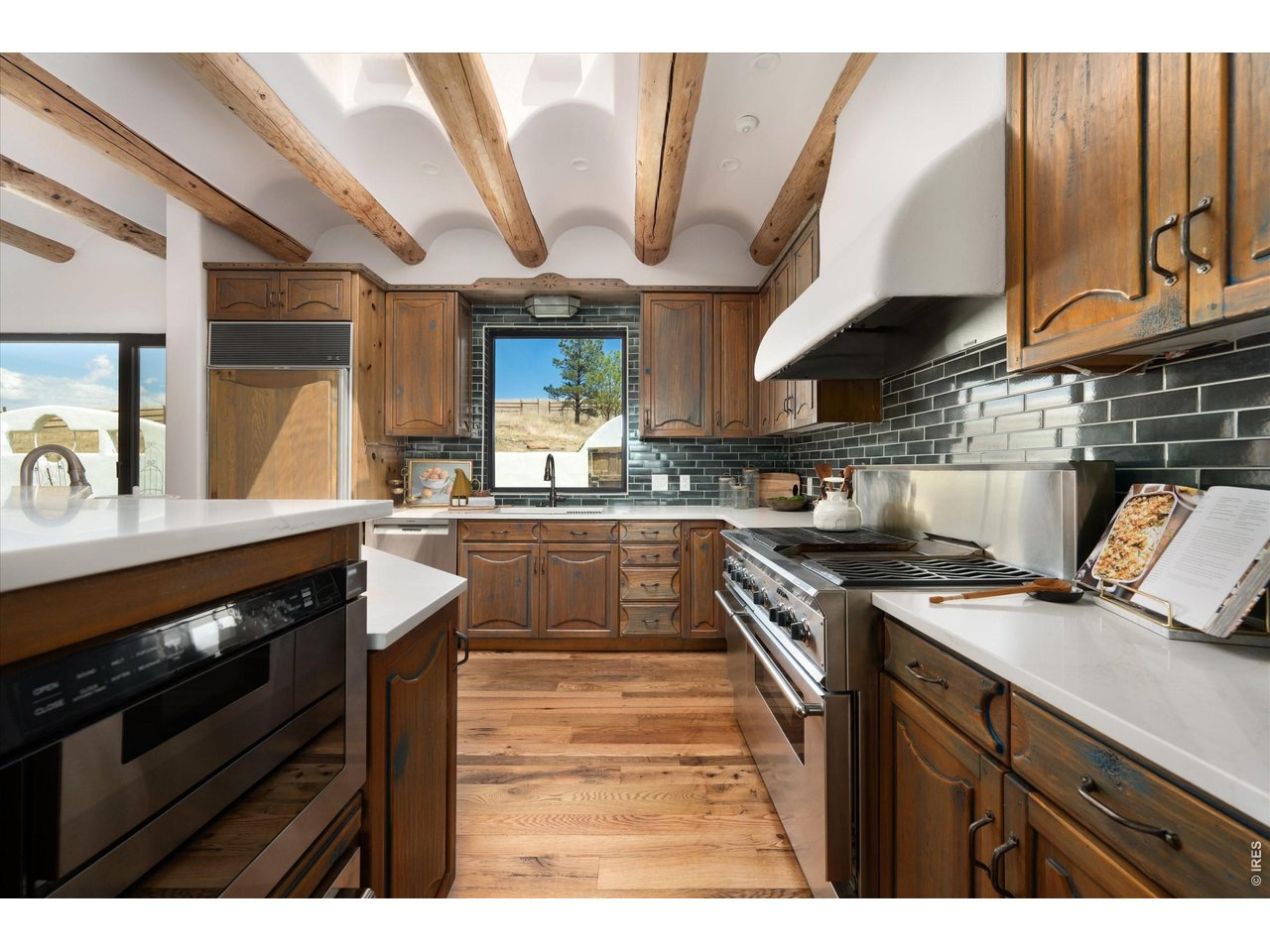 Property Photo 18 A chef's kitchen bathed in natural light from overhead skylights, complemented by custom wire burshed finsihed cabinetry and a seamless connection to the outdoors.