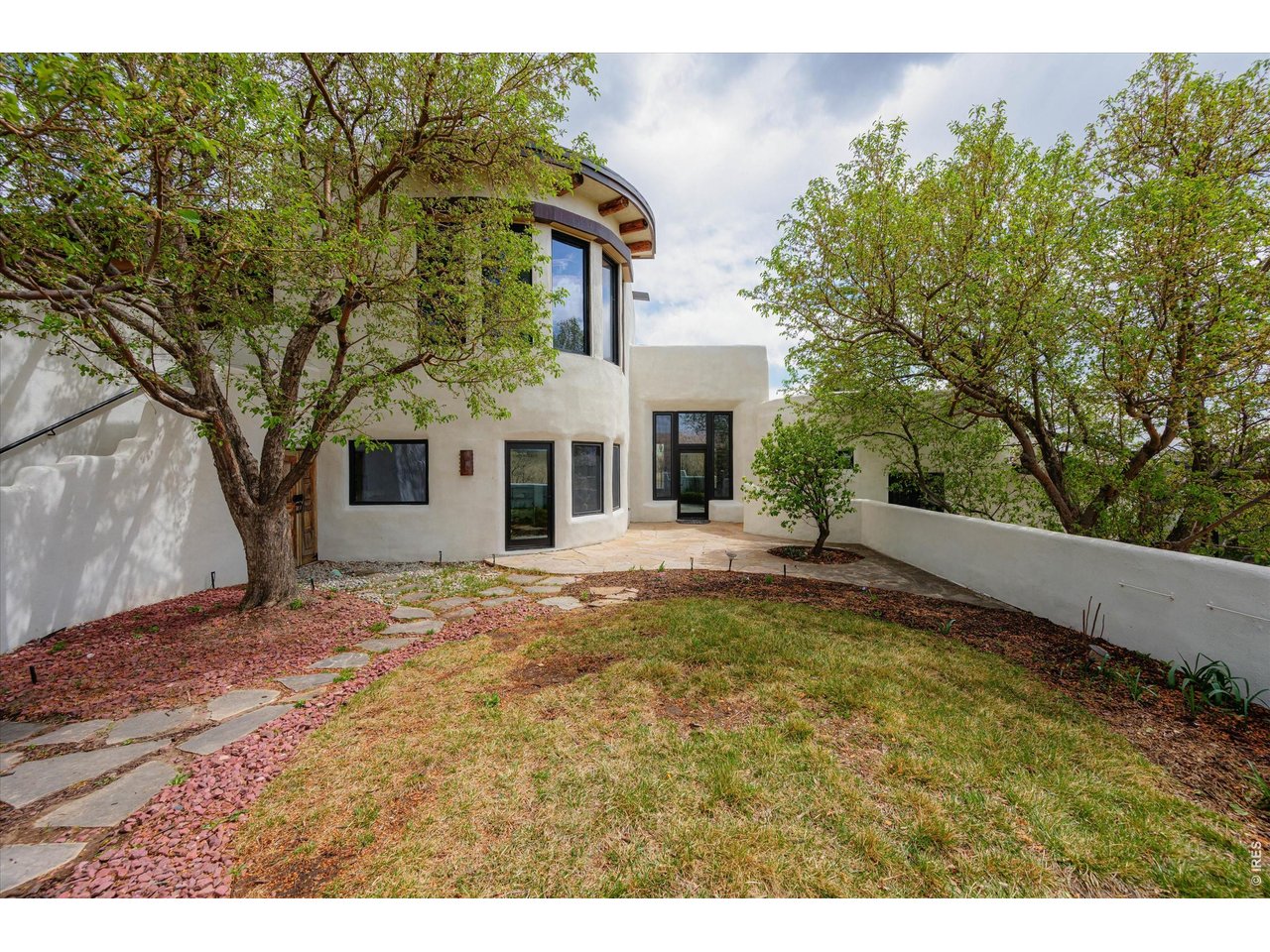 Property Photo 6 A private, tree-lined courtyard offers a serene outdoor retreat with natural shade, stone pathways, and seamless access to the home.