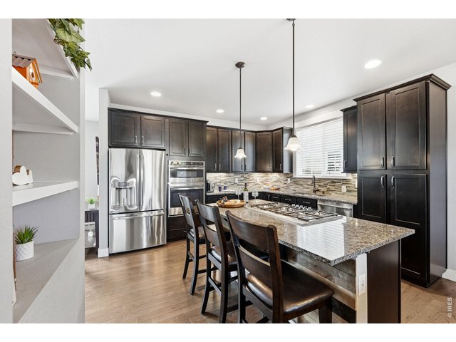 Property Photo 9 The gourmet kitchen is designed for both everyday living and entertaining, featuring a gas cooktop, center island with breakfast bar, ample cabinetry, and dining area.