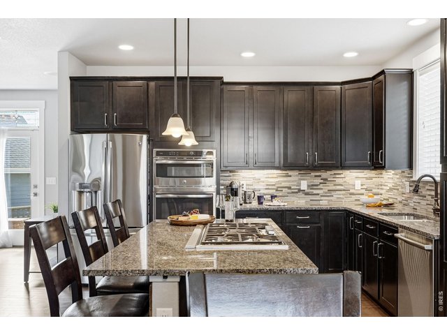 Property Photo 10 The gourmet kitchen is designed for both everyday living and entertaining, featuring a gas cooktop, center island with breakfast bar, ample cabinetry, and dining area.