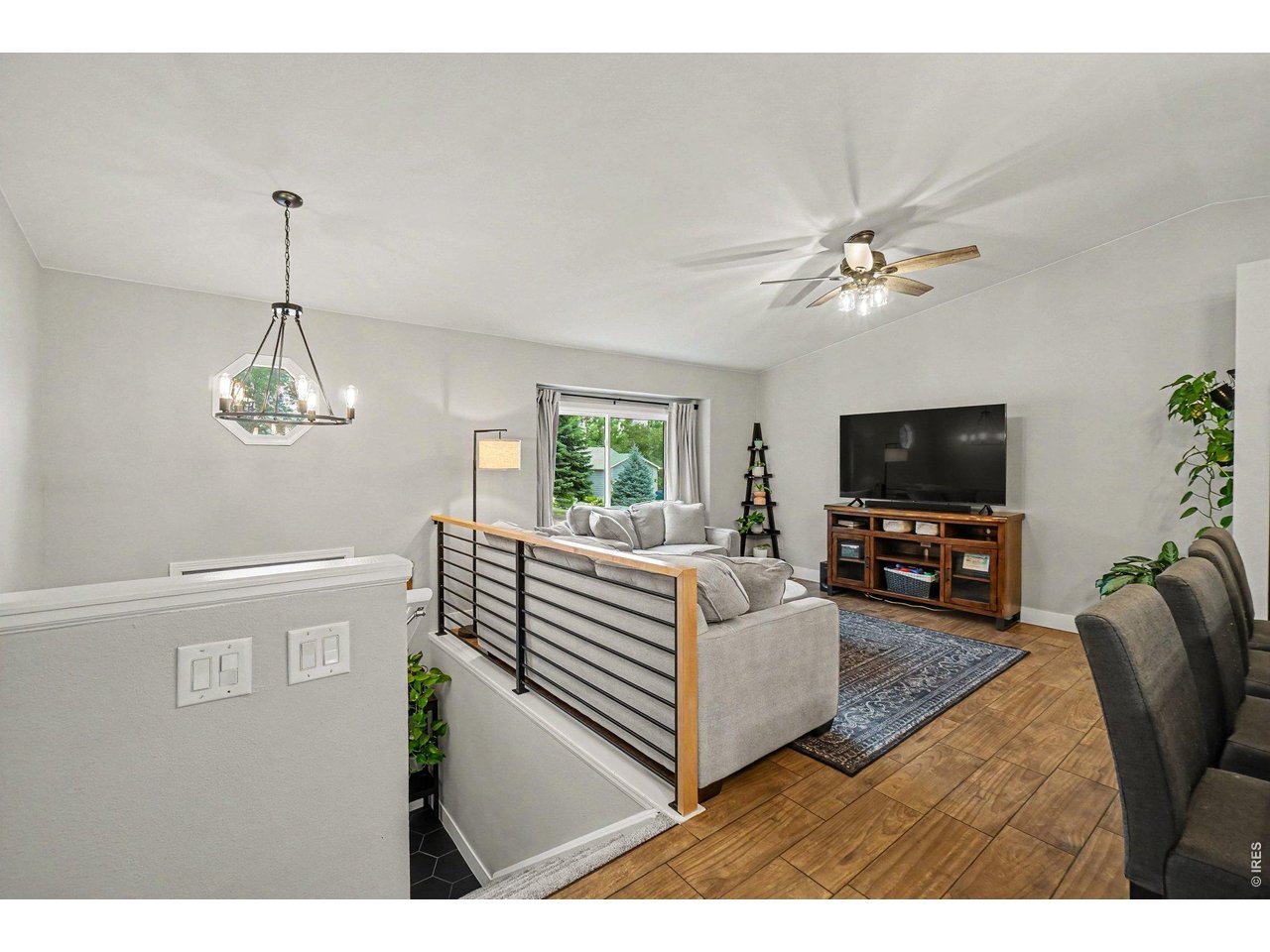 Property Photo 2 Sun-drenched room featuring warm wood-look flooring and a large picture window.