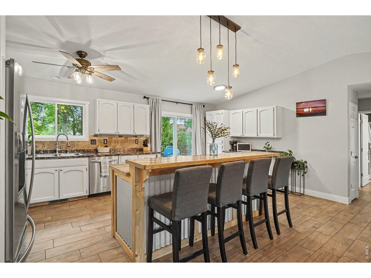 Property Photo 7 Bright kitchen equipped with white cabinetry, stone-look counters, and stainless steel appliances.