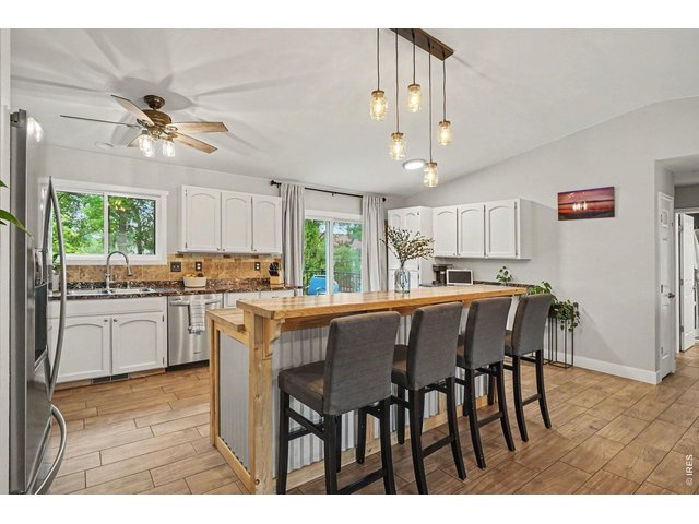 Property Photo 7 Bright kitchen equipped with white cabinetry, stone-look counters, and stainless steel appliances.