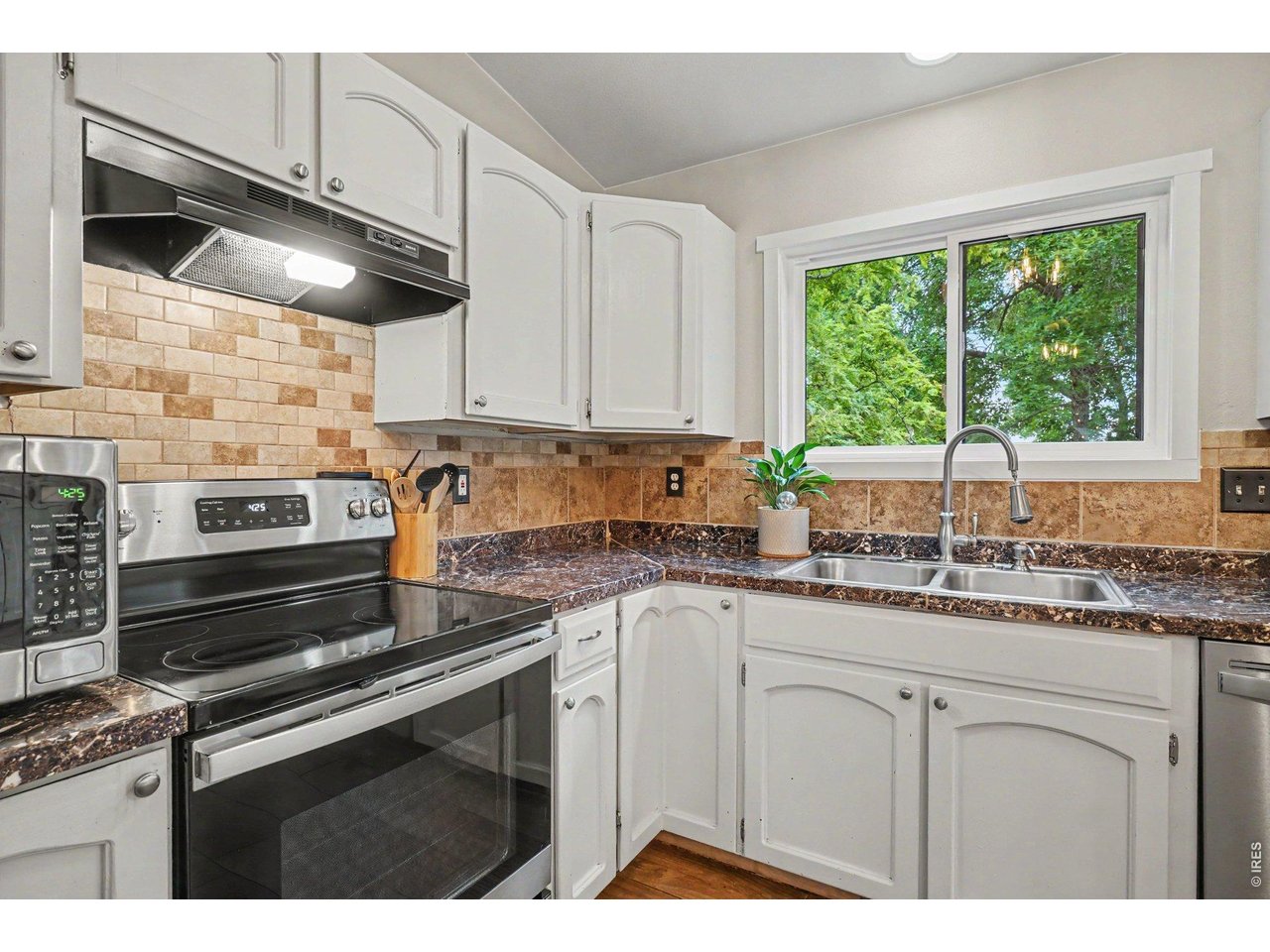 Property Photo 11 Efficient corner layout featuring a stainless steel range, timeless tile backsplash, and crisp white cabinetry.