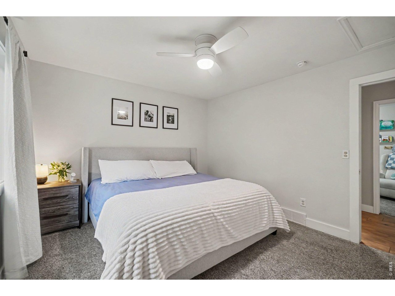 Property Photo 14 Spacious Primary bedroom featuring calm neutral tones, plush carpeting, and a modern white ceiling fan.
