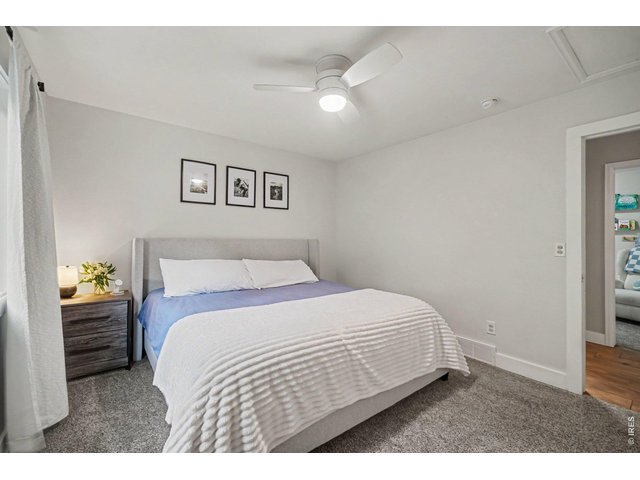 Property Photo 14 Spacious Primary bedroom featuring calm neutral tones, plush carpeting, and a modern white ceiling fan.