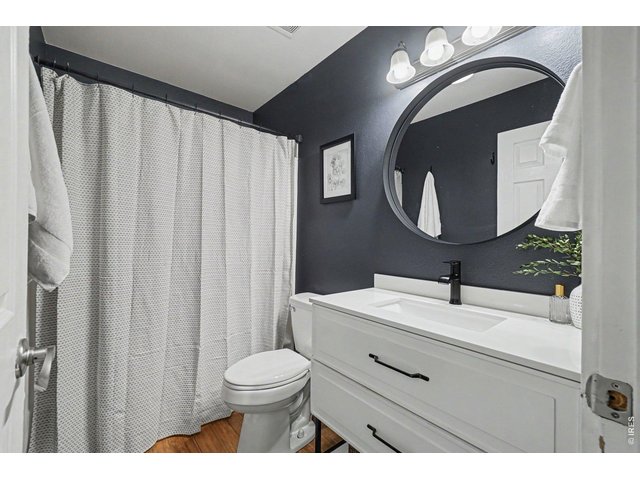Property Photo 16 Full bathroom showcasing dramatic charcoal walls, a crisp white vanity with modern black hardware, and a sleek round mirror.