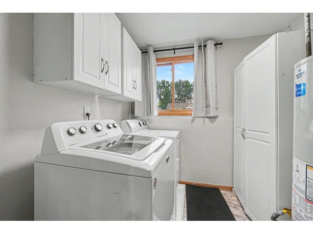 Property Photo 27 Functional laundry space equipped with a modern top-loading washer and dryer, white overhead storage cabinets, a tall utility closet, and a bright window.