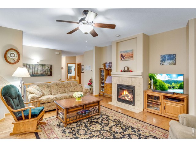 Property Photo 7 Large, open family room featuring a ceiling fan and a gas fireplace with a blower for added utility savings, along with a tile backsplash