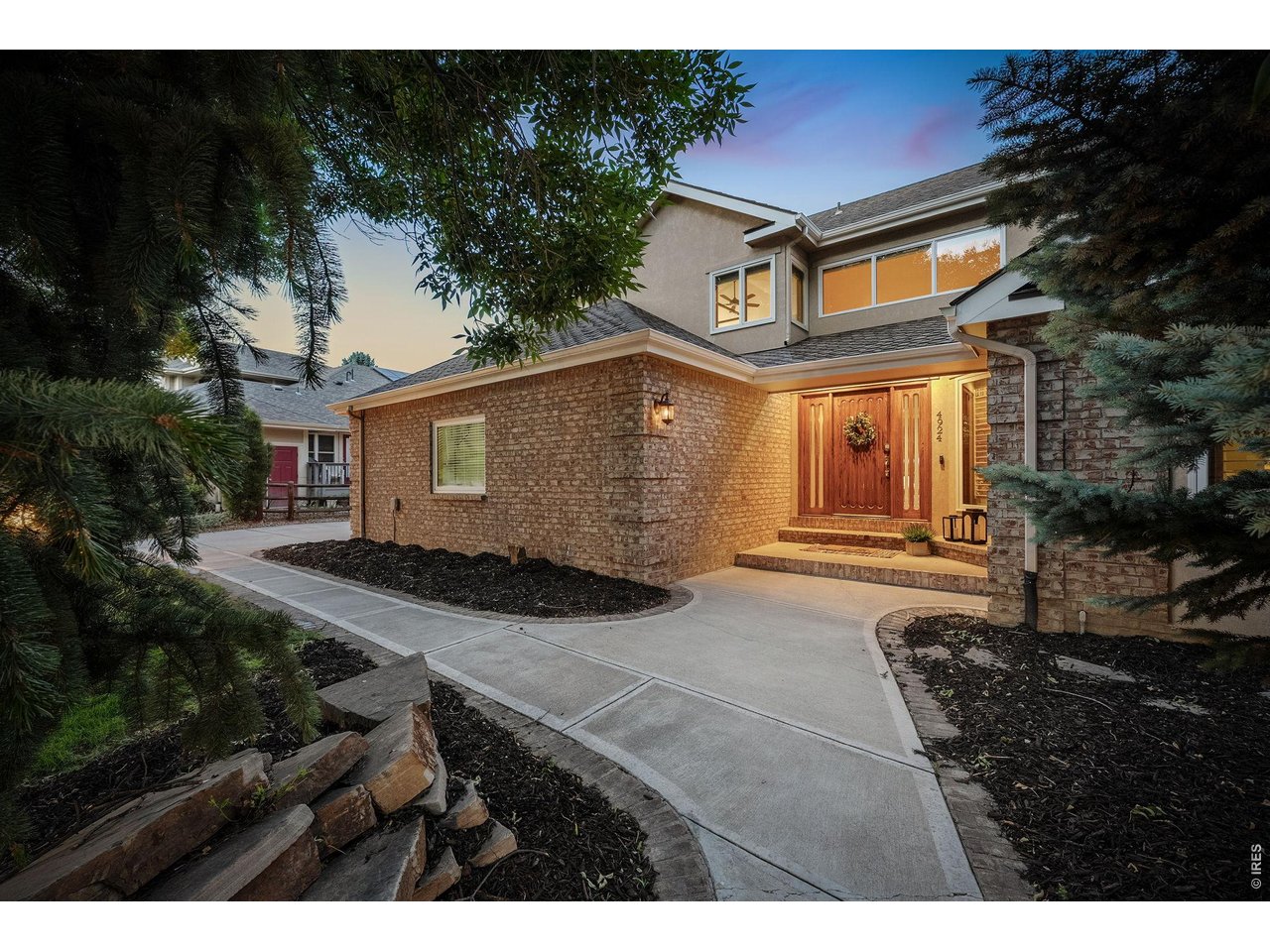 Property Photo 3 From the moment you arrive, the custom wood door creates a stunning first impression, inviting you inside, while timeless brick accents and soft evening lighting highlight the home's elegant curb appeal.