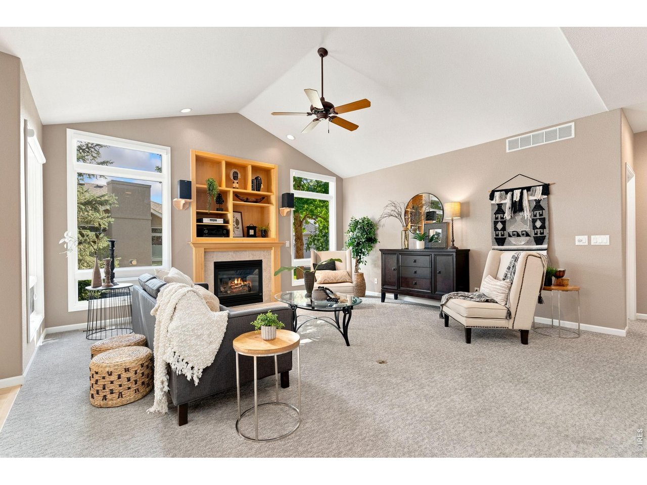 Property Photo 7 Two large floor to ceiling windows with gas fireplace and built in shelving in living room.