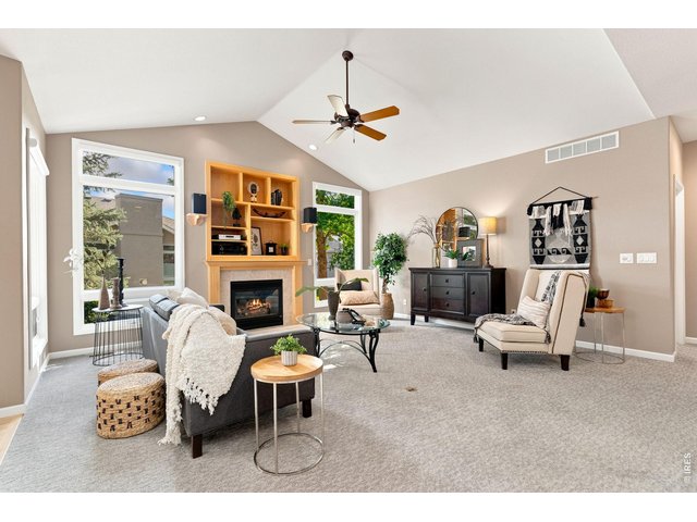 Property Photo 7 Two large floor to ceiling windows with gas fireplace and built in shelving in living room.