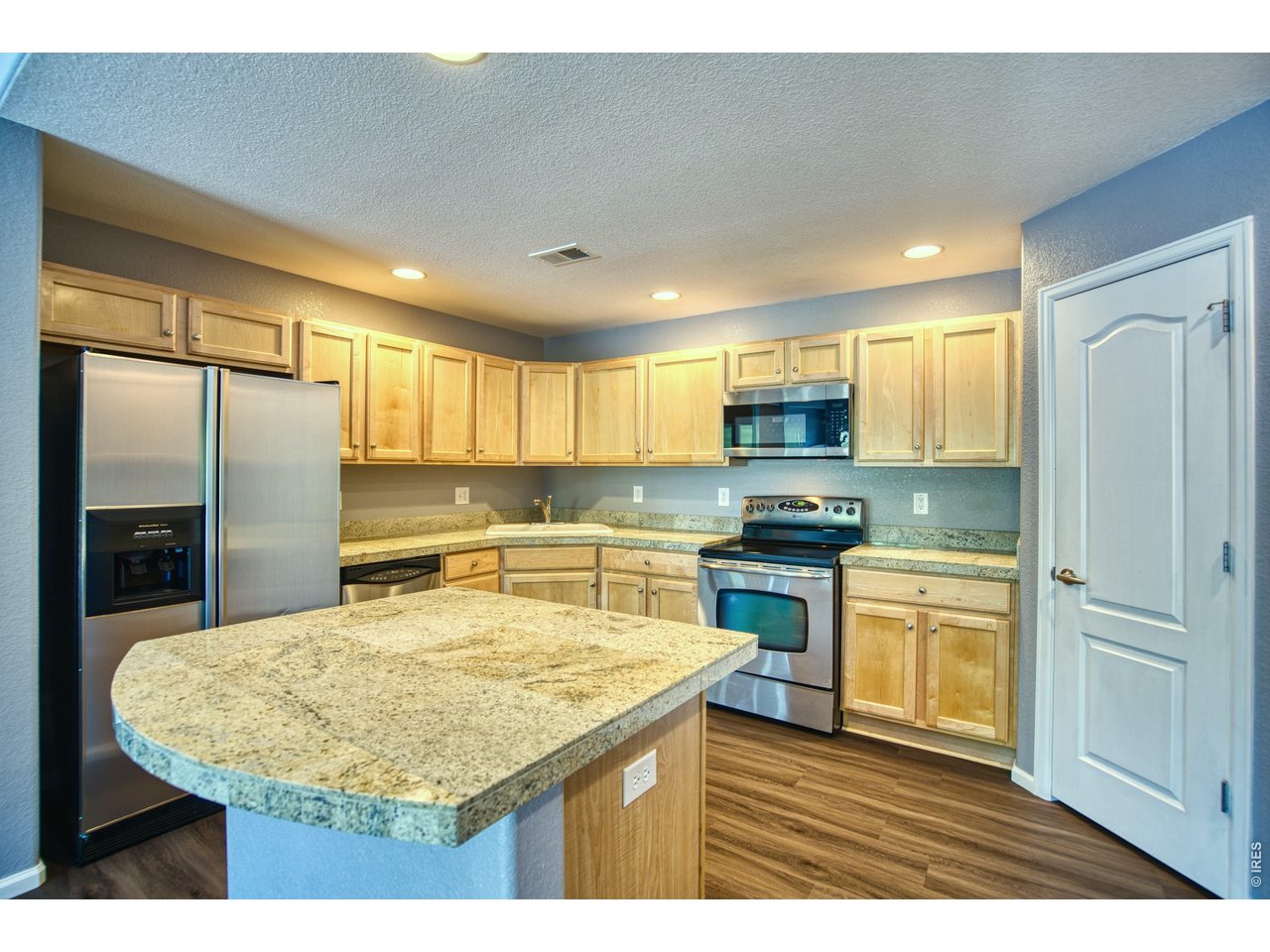 Property Photo 4 Pleasant kitchen provides ample maple cabinets w/pull-outs, tile granite counters & center island with snack bar for stools.