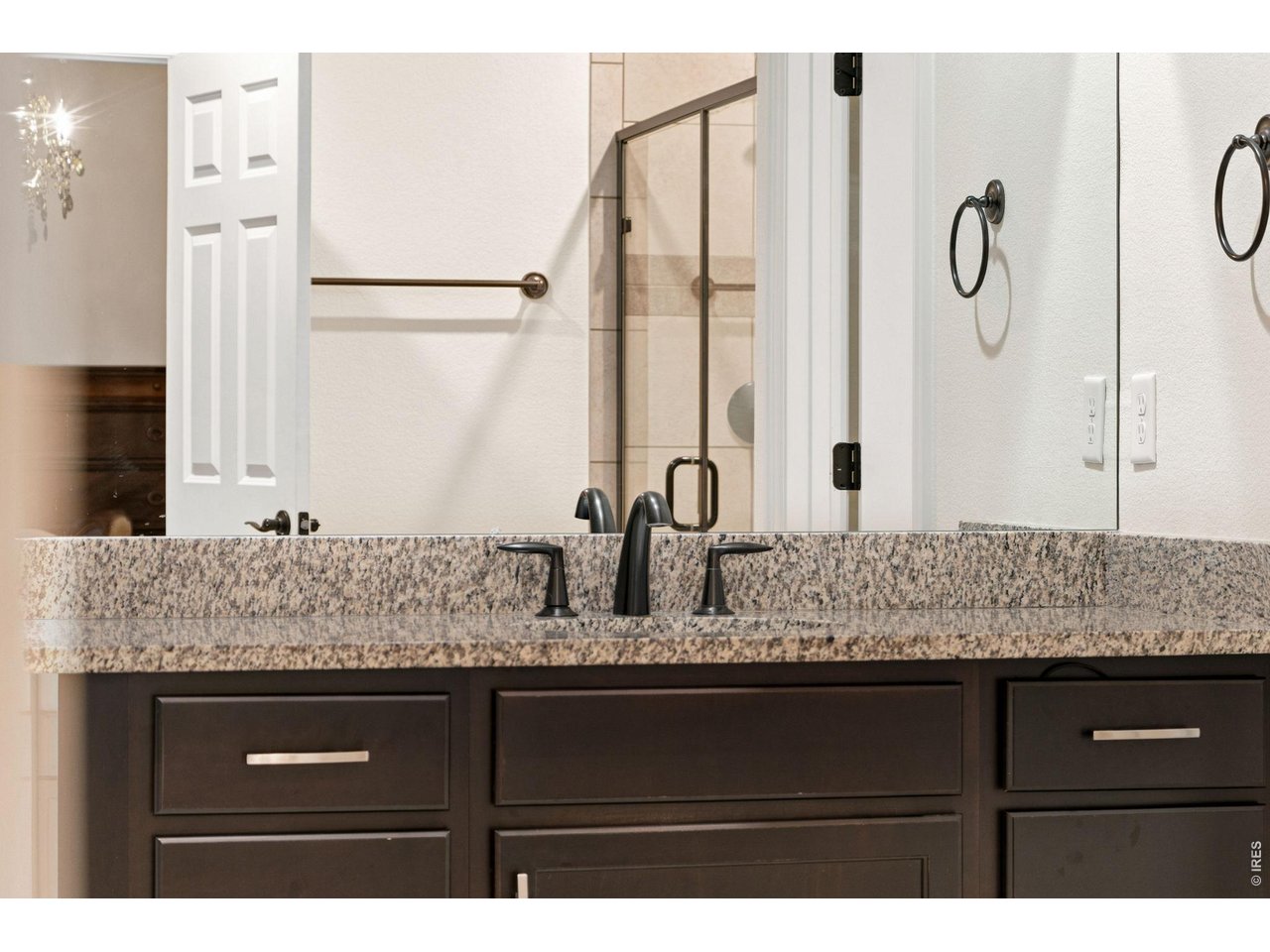 Property Photo 29 Chocolate cabinets, granite countertops and classic hardware add charm to the ensuite primary bathroom.
