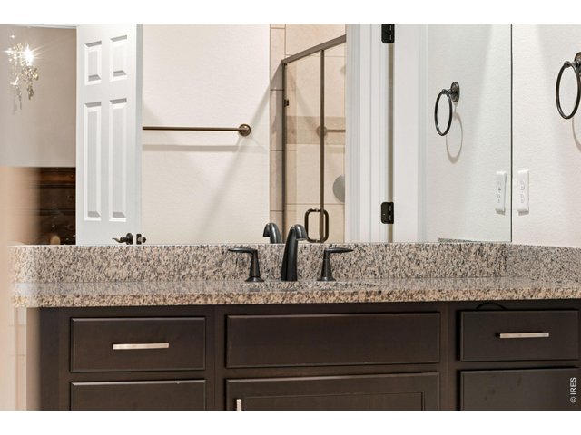 Property Photo 29 Chocolate cabinets, granite countertops and classic hardware add charm to the ensuite primary bathroom.